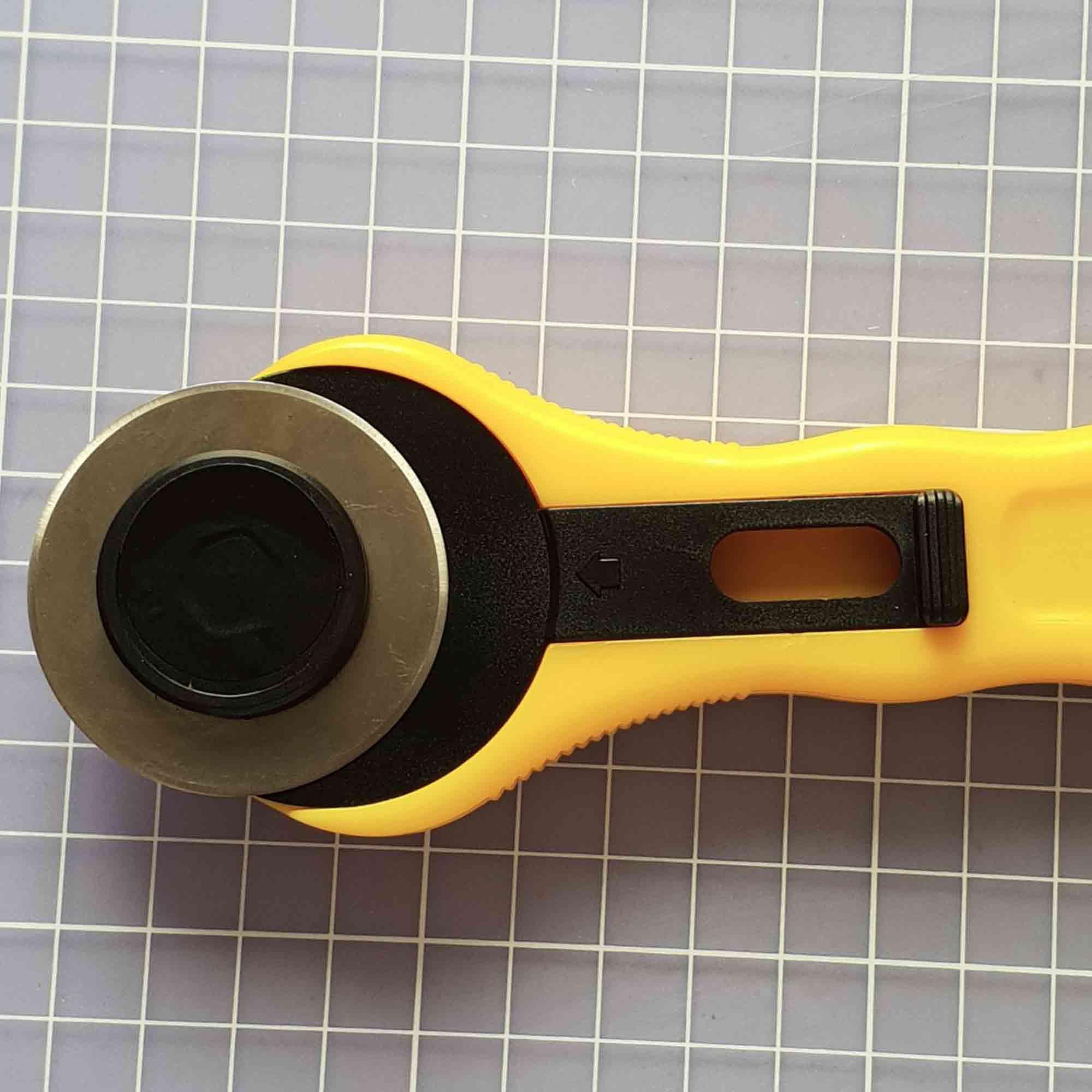 Rollschneider mit ergonomischem Griff und fixierter 45 mm Klinge auf Schneidematte mit Stoff Rollschneider mit 45 mm Klinge zum präzisen Schneiden von Stoff & Papier