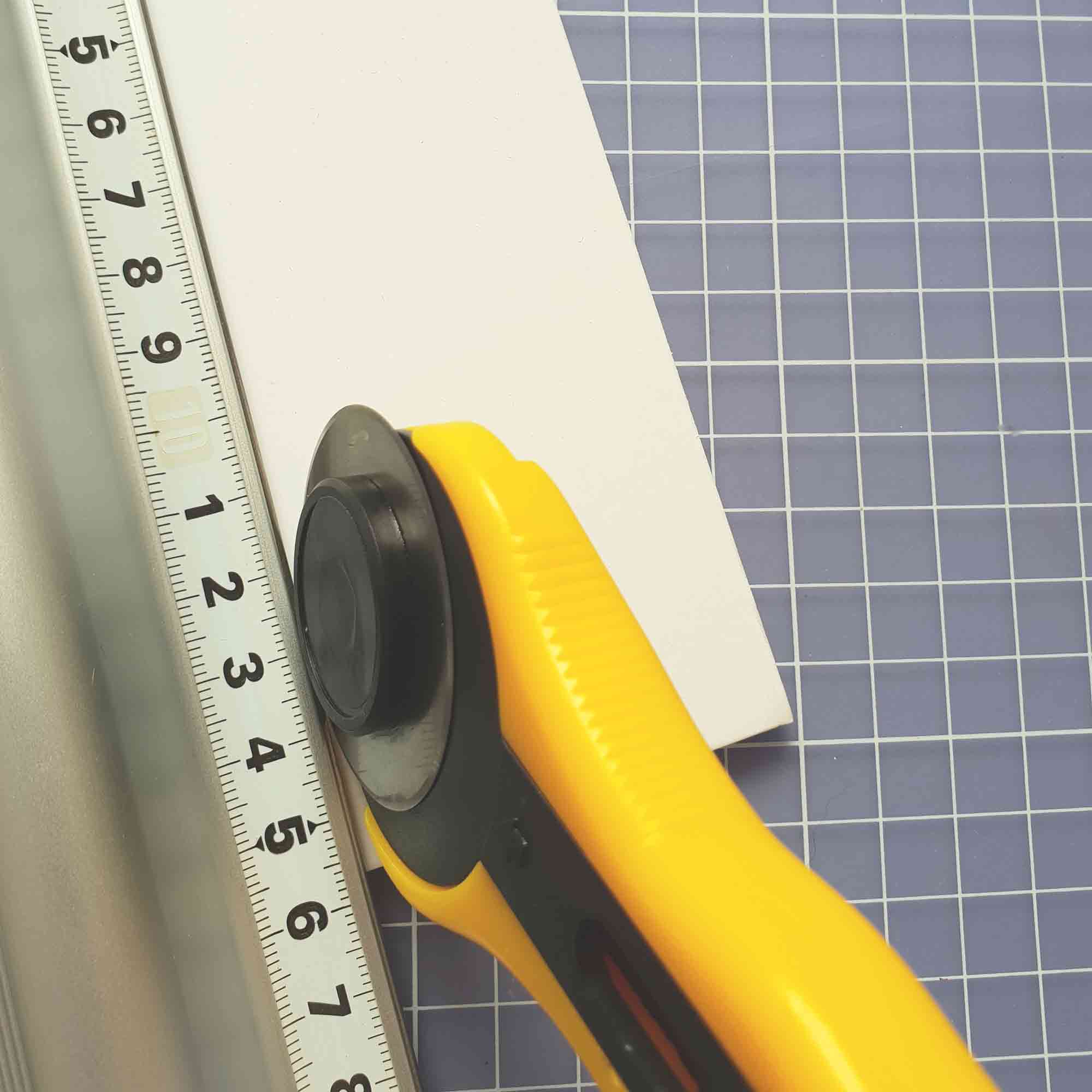 Detailaufnahme eines ergonomischen Rollschneiders mit Sicherheitsarretierung im Einsatz Rollschneider 45 mm mit Sicherheitsfunktion beim Schneiden von Papier