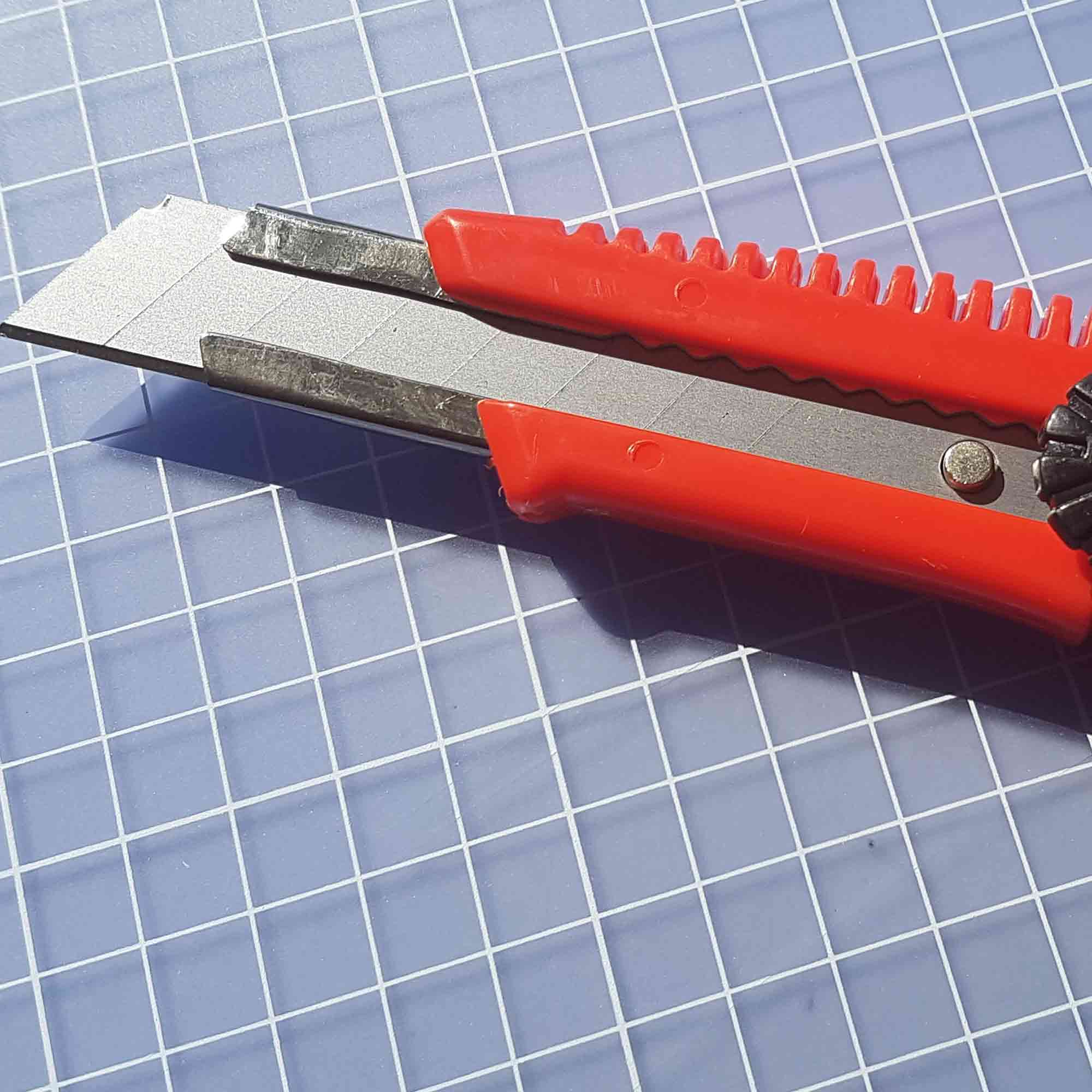 Detailaufnahme beim präzisen Schnitt durch Folie oder Karton – Einsatzbereich Verpackung. Standardmesser 18 mm beim Schneiden von Verpackungsmaterial